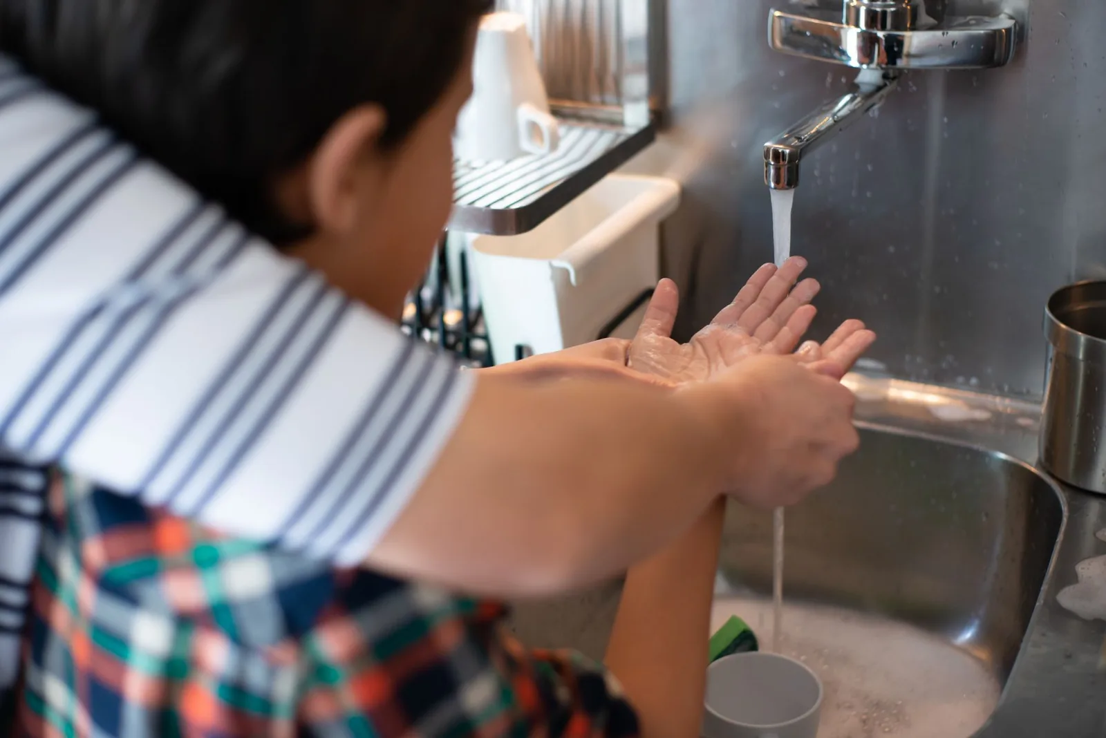 Adult helping a child wash hands at a sink